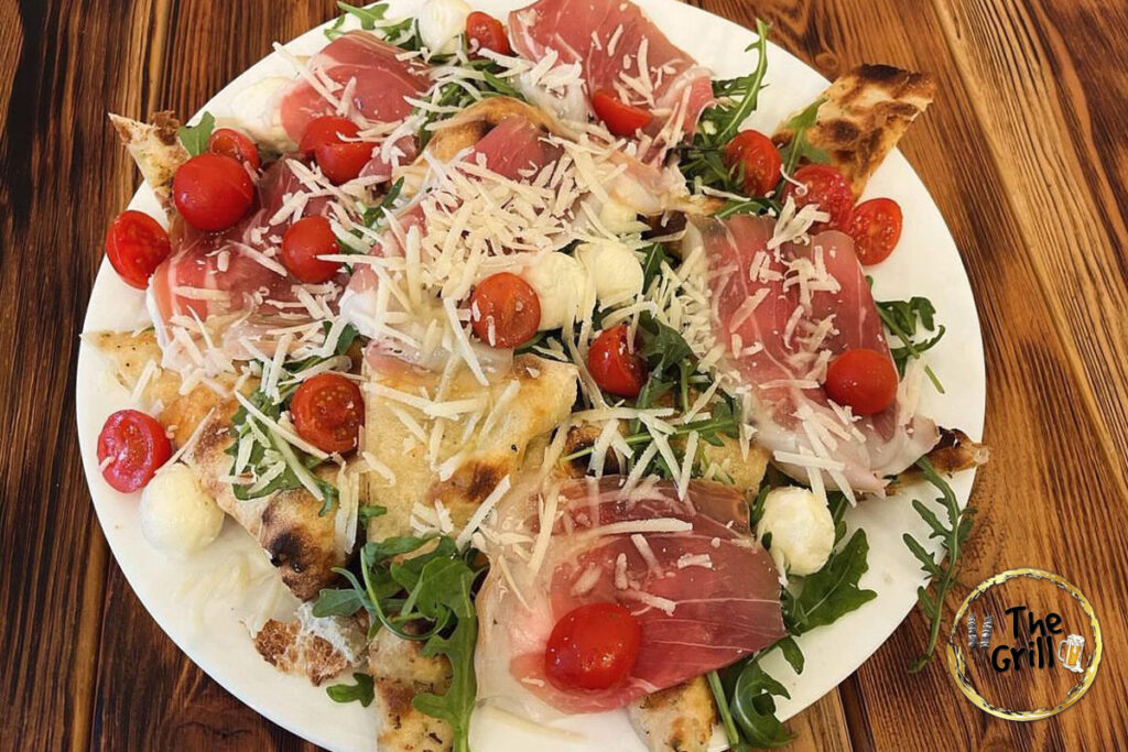 Prosciutto crudo, bocconcini di mozzarella, pomodorini, rucola e scaglie di grana, con focaccia bianca
